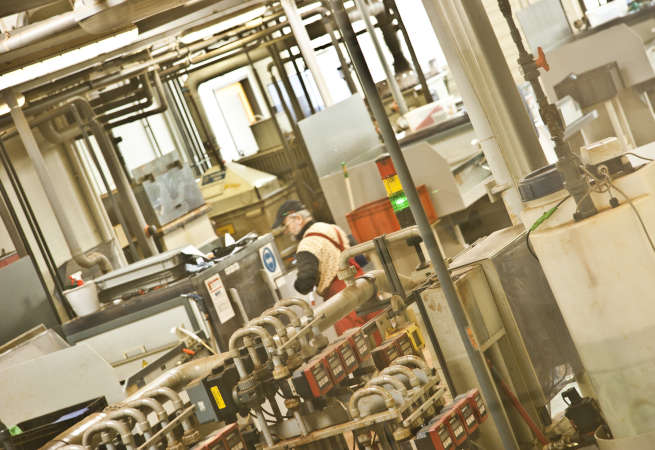 Historische Aufnahme aus dem Produktionsbereich der Metaq GmbH mit Produktionsmaschine und Rohrleitungen