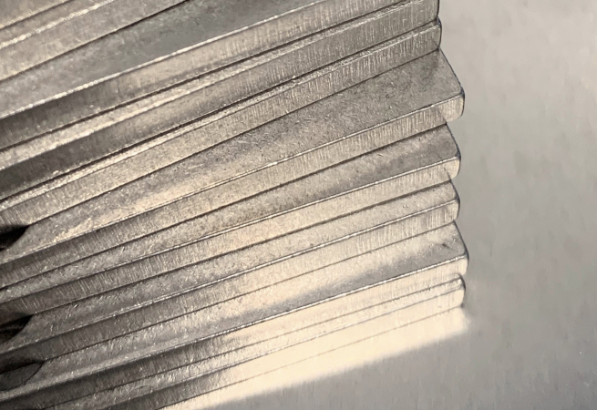 Makroaufnahme von gestapelten Formteilen aus Metall mit Fokus auf die Laserschnittkanten