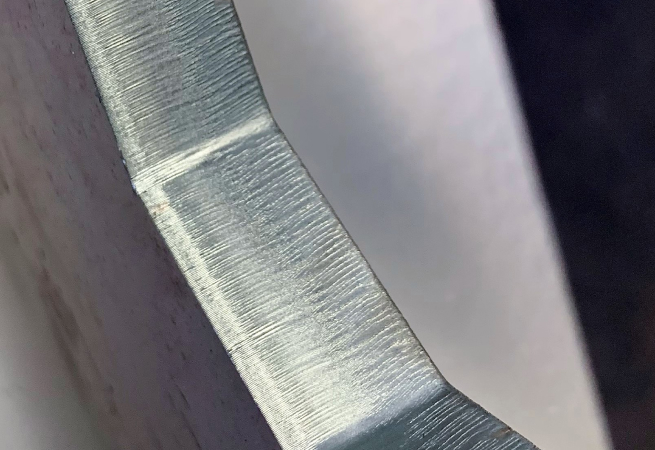 Makroaufnahme eines mit einem Faserlaser geschnittenen Formteils aus Metall mit Fokus auf die Schnittkante
